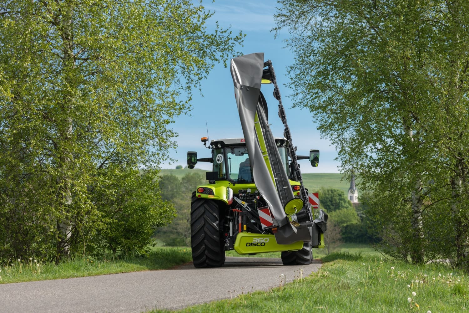 CLAAS Tractor driving down the road with the CLAAS DISCO rear mower folded