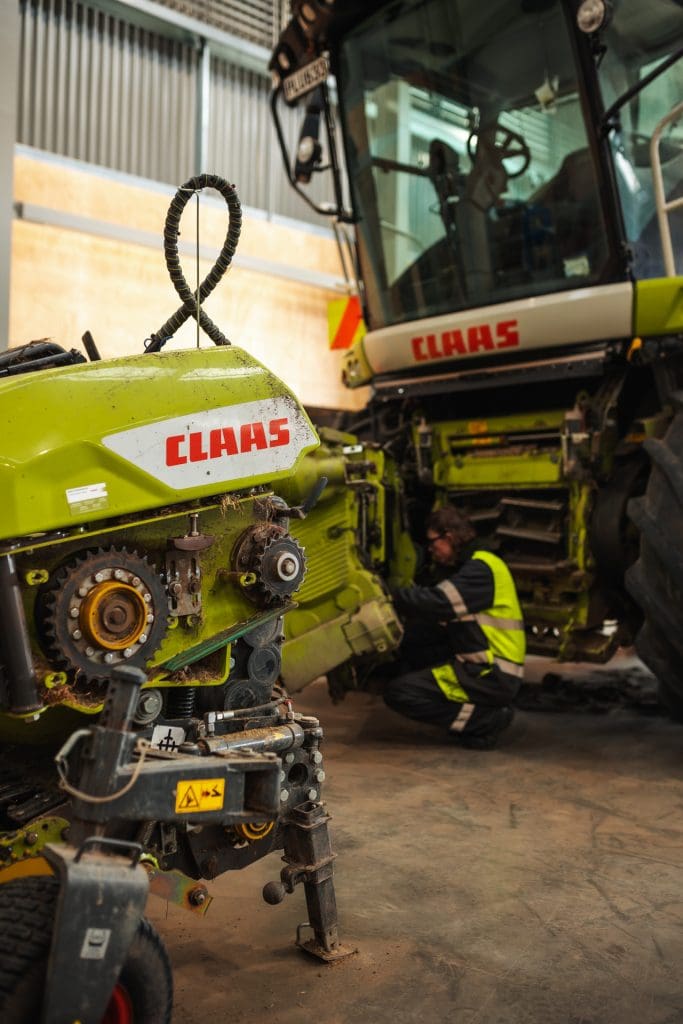 image of mechanic inspecting the front of jaguar, forage harvester