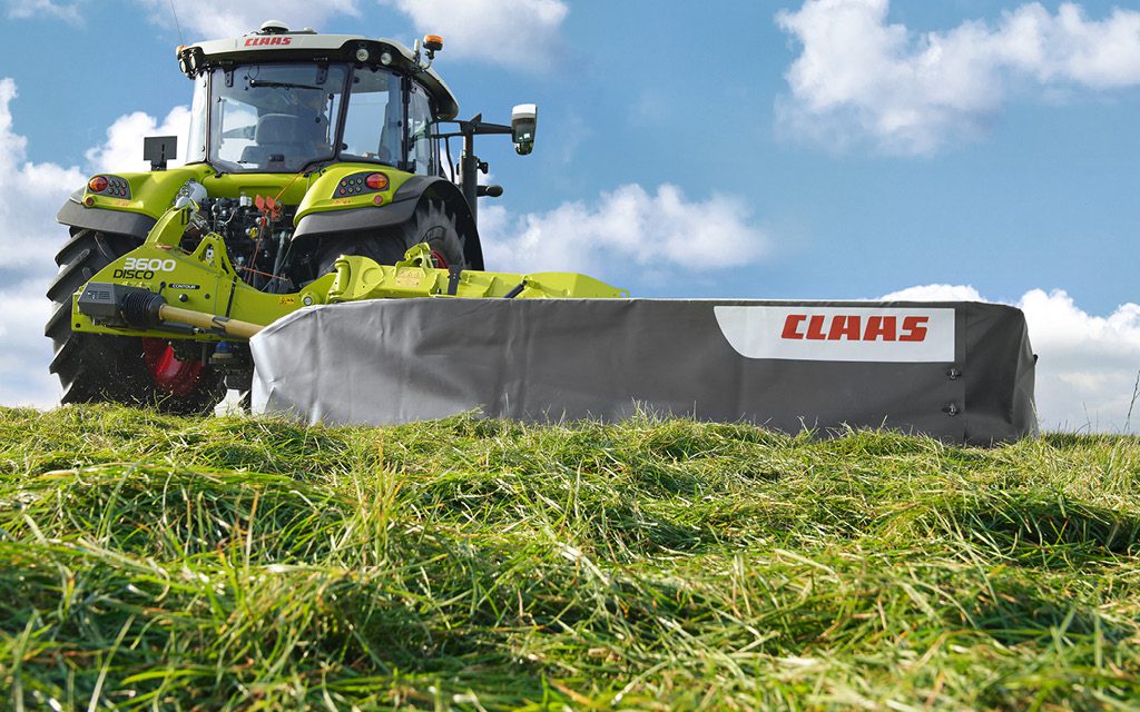 claas tractor and claas disco mower operating and cutting grass